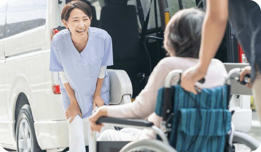 介護車両の前で笑顔を見せる訪問スタッフ