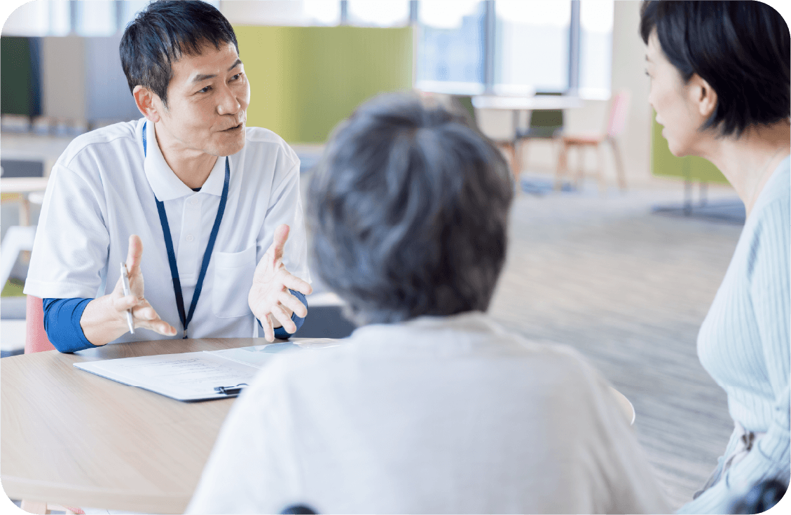 介護に関する相談を受けるケアマネージャーとスタッフ。高齢夫婦との打ち合わせ。